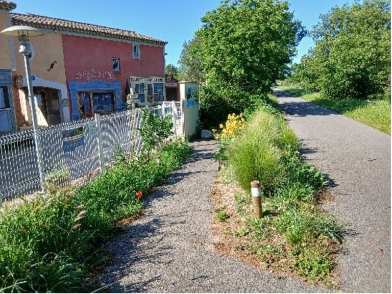 La pista ciclabile fiancheggiata da fiori, lungo una casa rosa