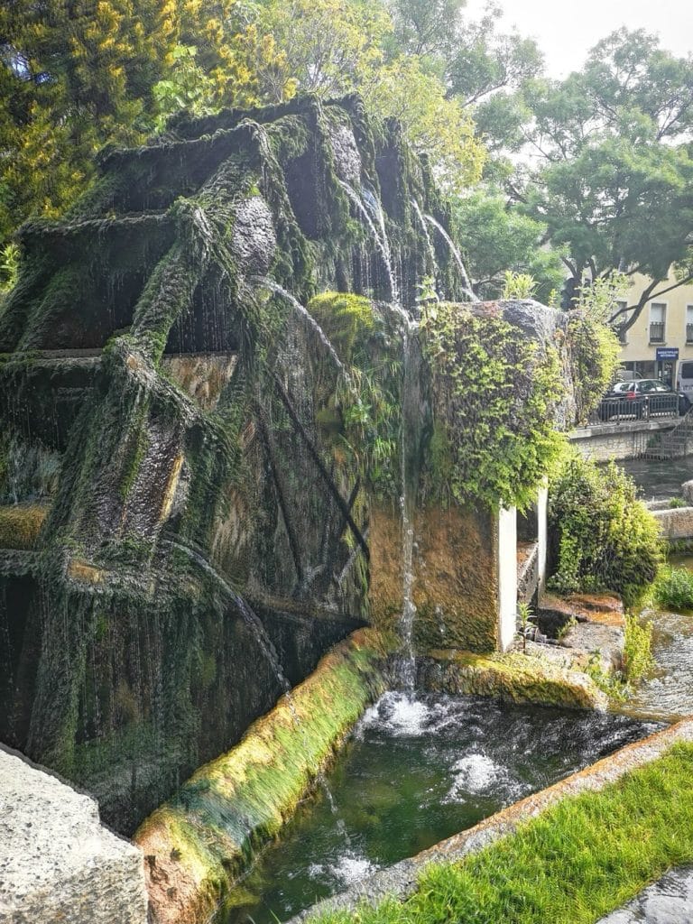 A foam-covered waterwheel on a canal in L’Isle-sur-la-Sorgue